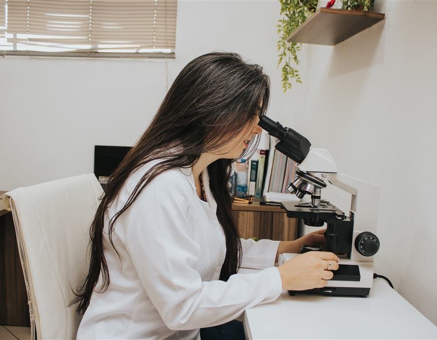 M.V. Aline Santos analisando uma lâmina no microscópio