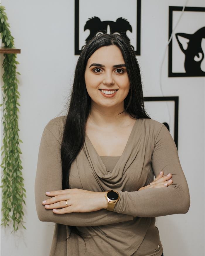 M.V. Aline Santos no consultório veterinário, de braços cruzados e sorrindo