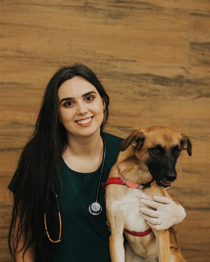 M.V. Aline Santos de pijama cirúrgico abraçando um cachorro paciente
